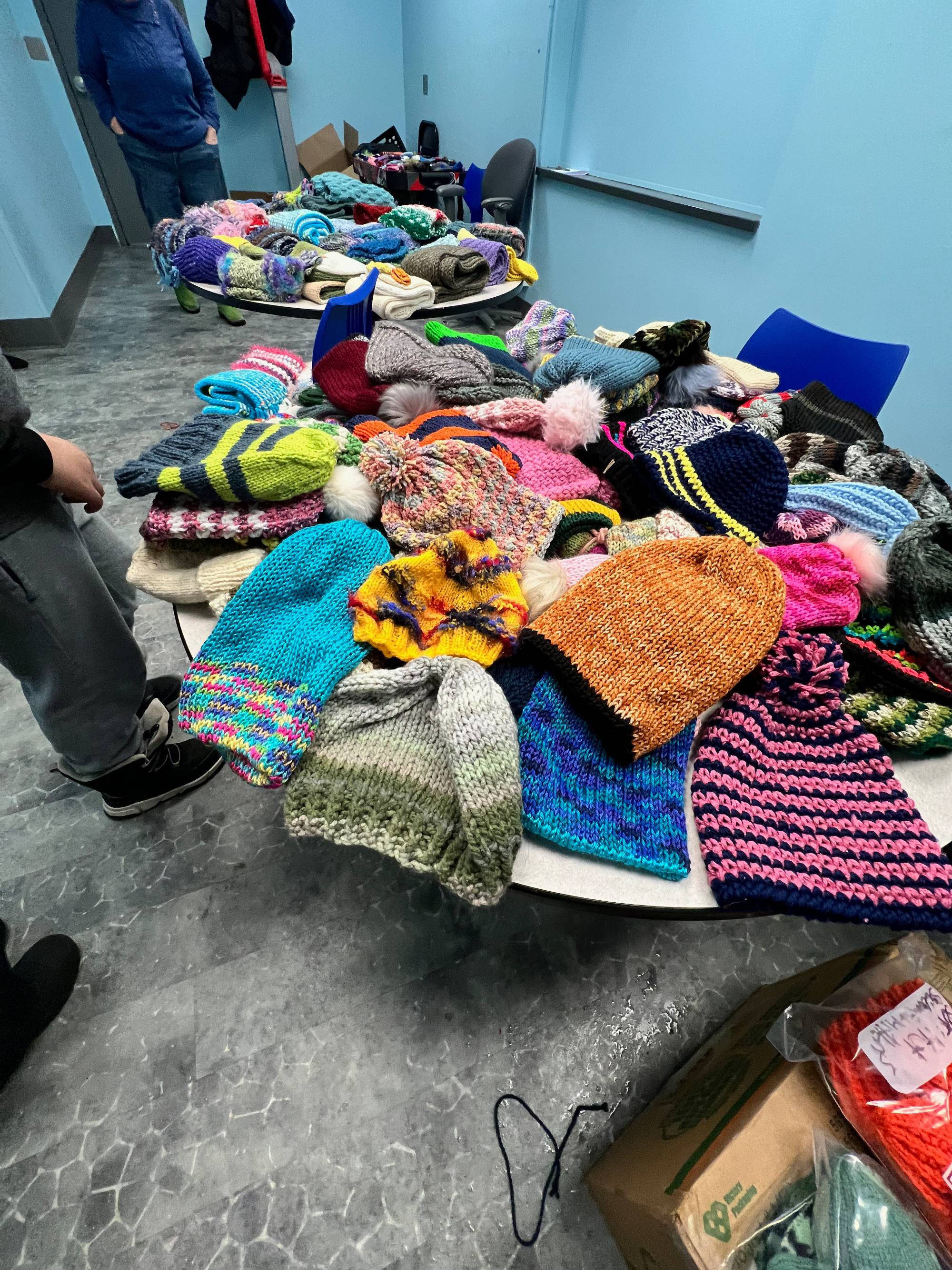 Two tables full of colorful knitted hats, scarves, and mittens.